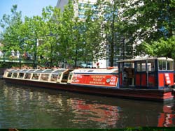 trip boat on a tree lined section of canal in summer