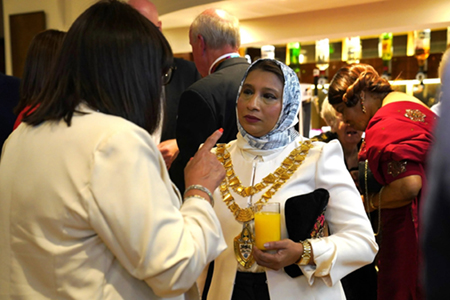 two people in deep conversation, one wearing a chain of office